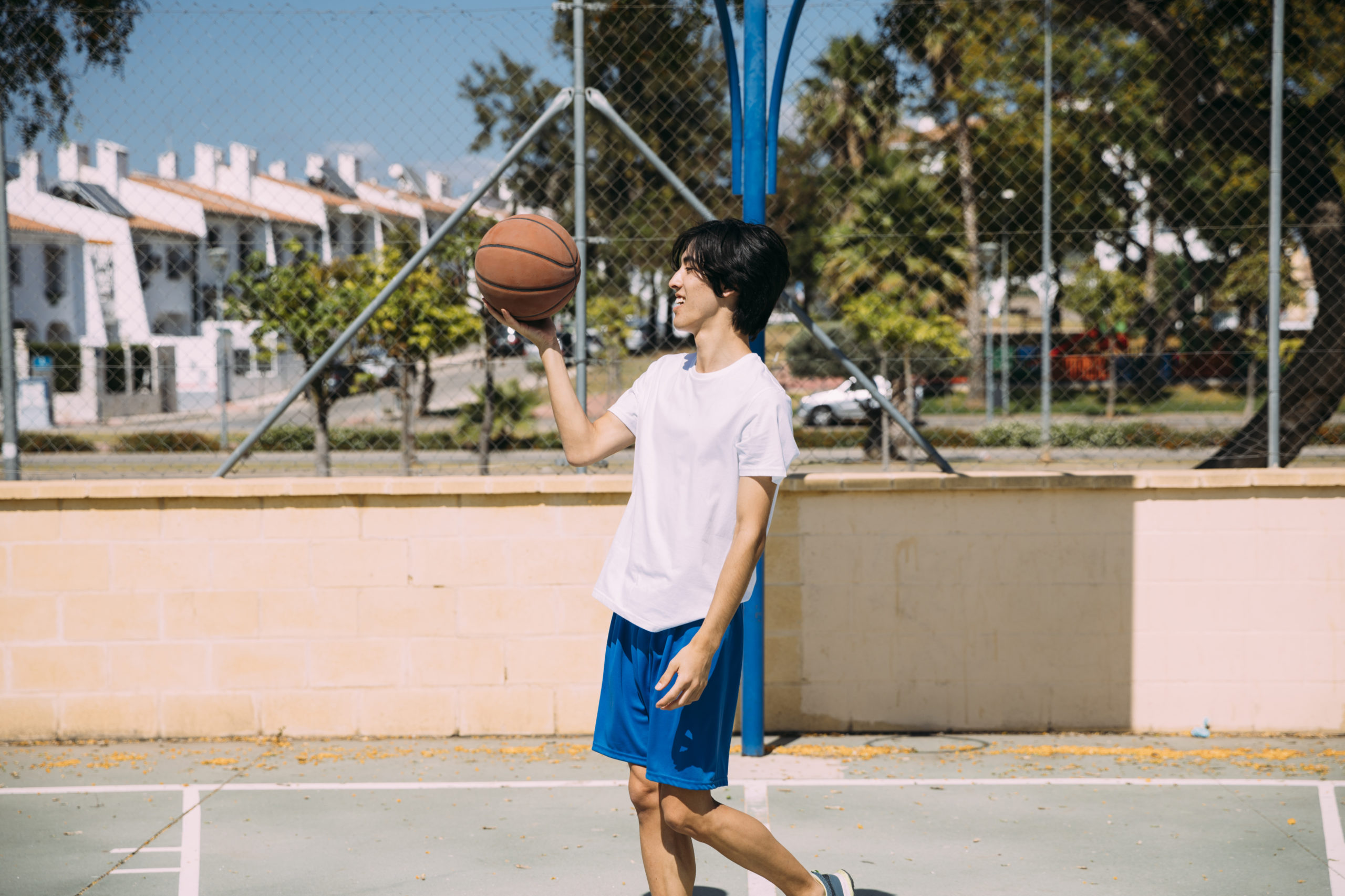 ethnic-male-holding-basketball-while-standing-playground